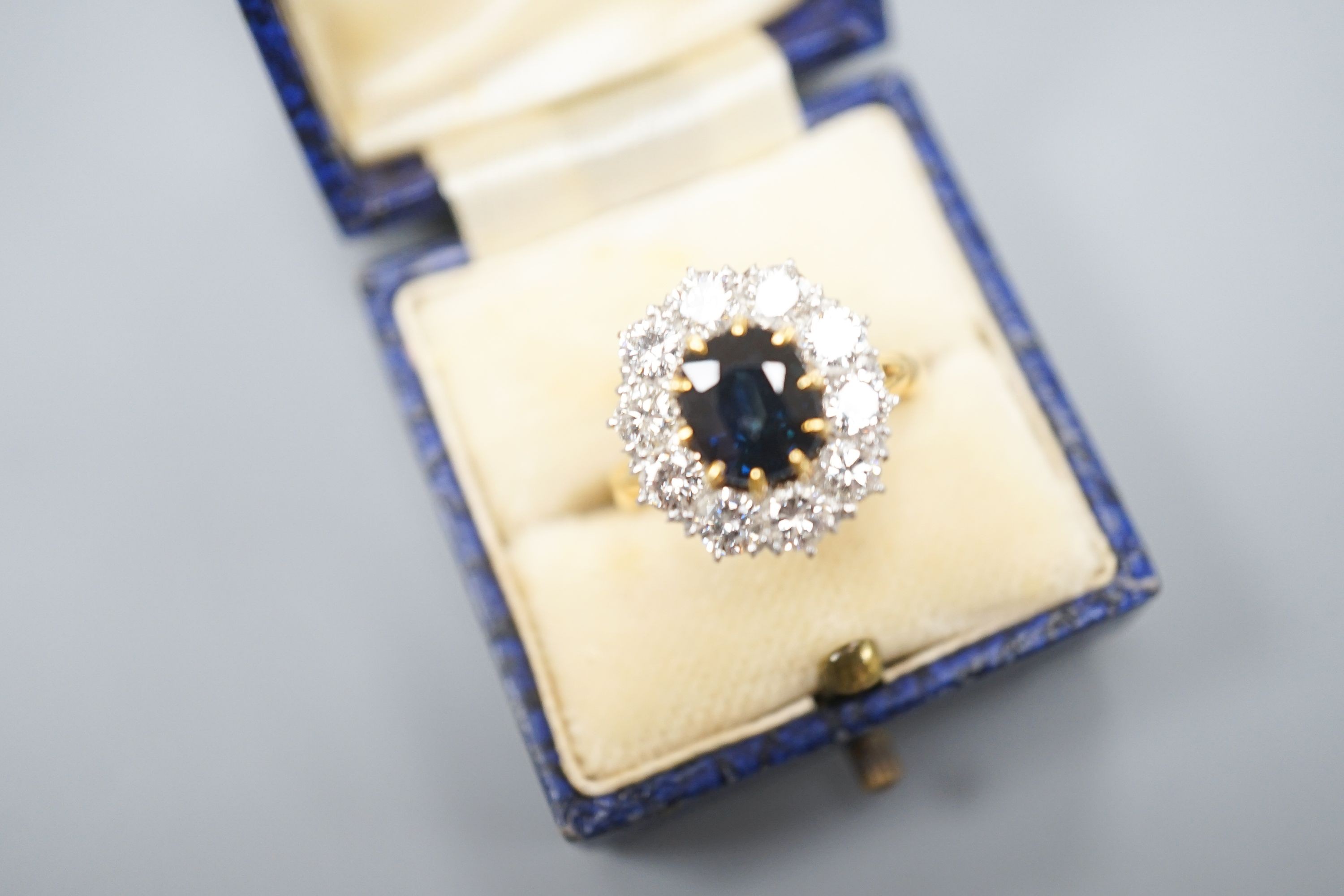 A modern 18ct gold, sapphire and diamond set oval cluster ring, size P/Q, gross weight 6.2 grams.